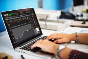 Eine Person analysiert auf einem Laptop ein interaktives Finanzdiagramm mit Kursbewegungen und Marktinformationen – eine typische Szene aus dem digitalen Handel mit ETFs im modernen Anlageumfeld.