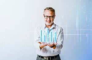 Älterer Mann in Businesskleidung hält digitale Balkendiagramme in den Händen – symbolische Darstellung von finanzieller Planung und strategischer Altersvorsorge.